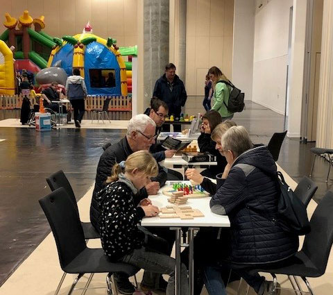 Jung und Alt sitzen an den Tischen und probieren sich an inklusiven Spielen aus.