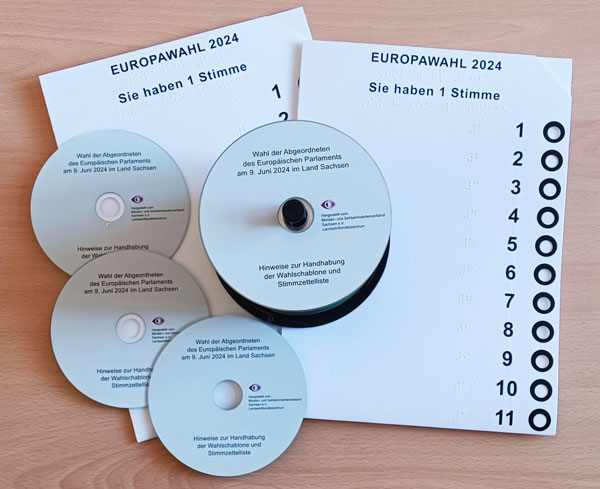 Es sind zwei Wahlschablonen und einige Stimmzettel-CDs zu sehen.